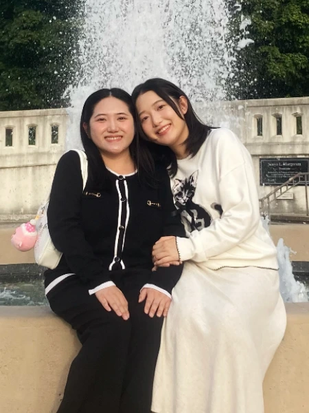 Daffodil and Heaven Xiong smile together by a fountain on Purdue University’s campus.
