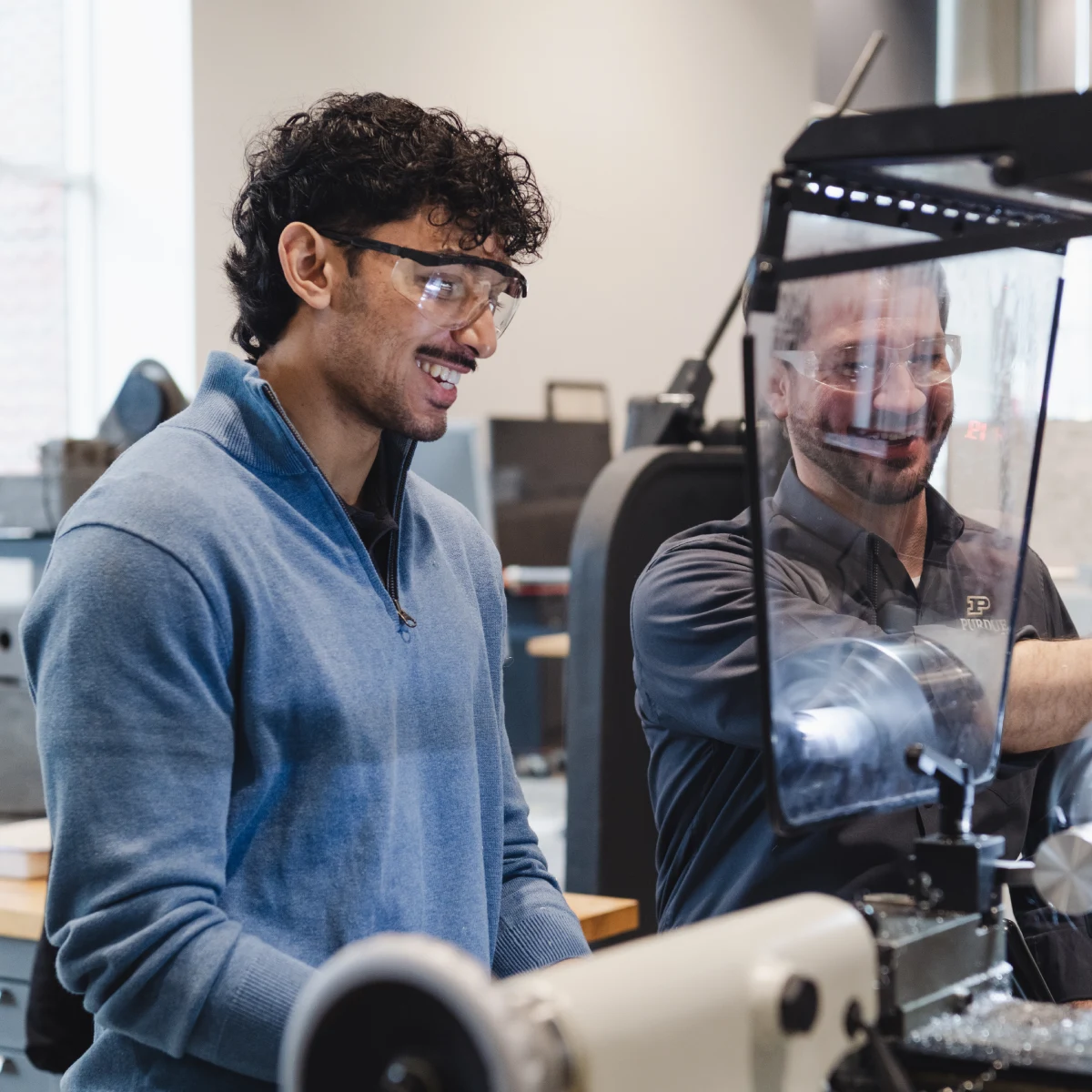 Student working with employee at machine