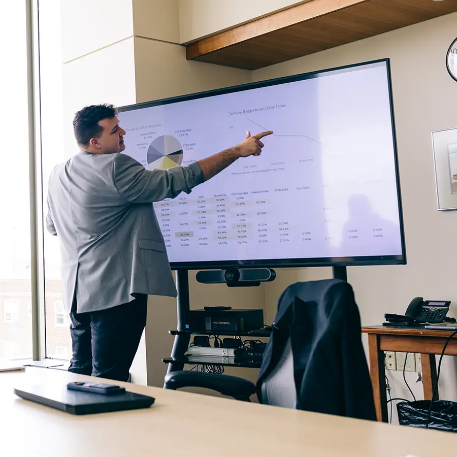 A man gives a presentation and points at a screen