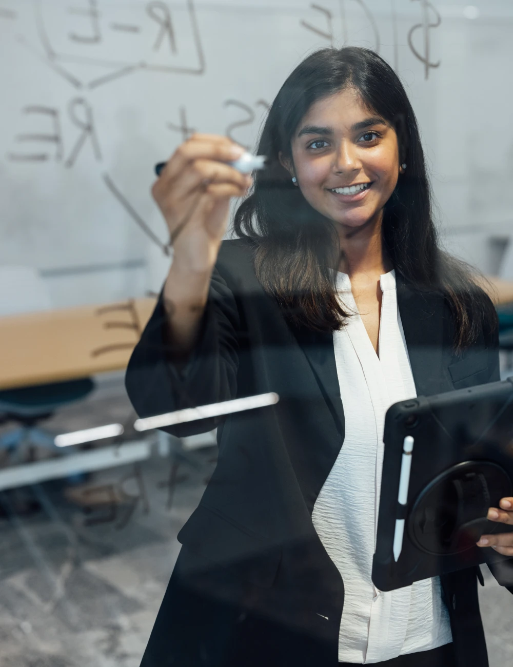 Business student writing equation on glass board