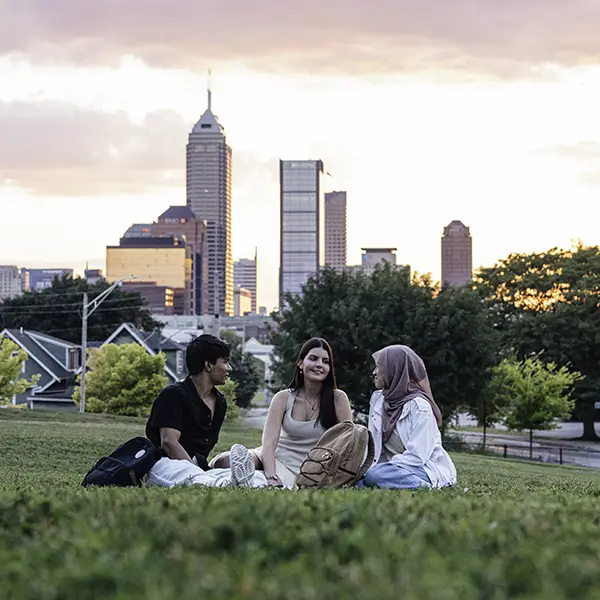 Students sitting on a picnic blanket with the Indianapolis skyline in the background